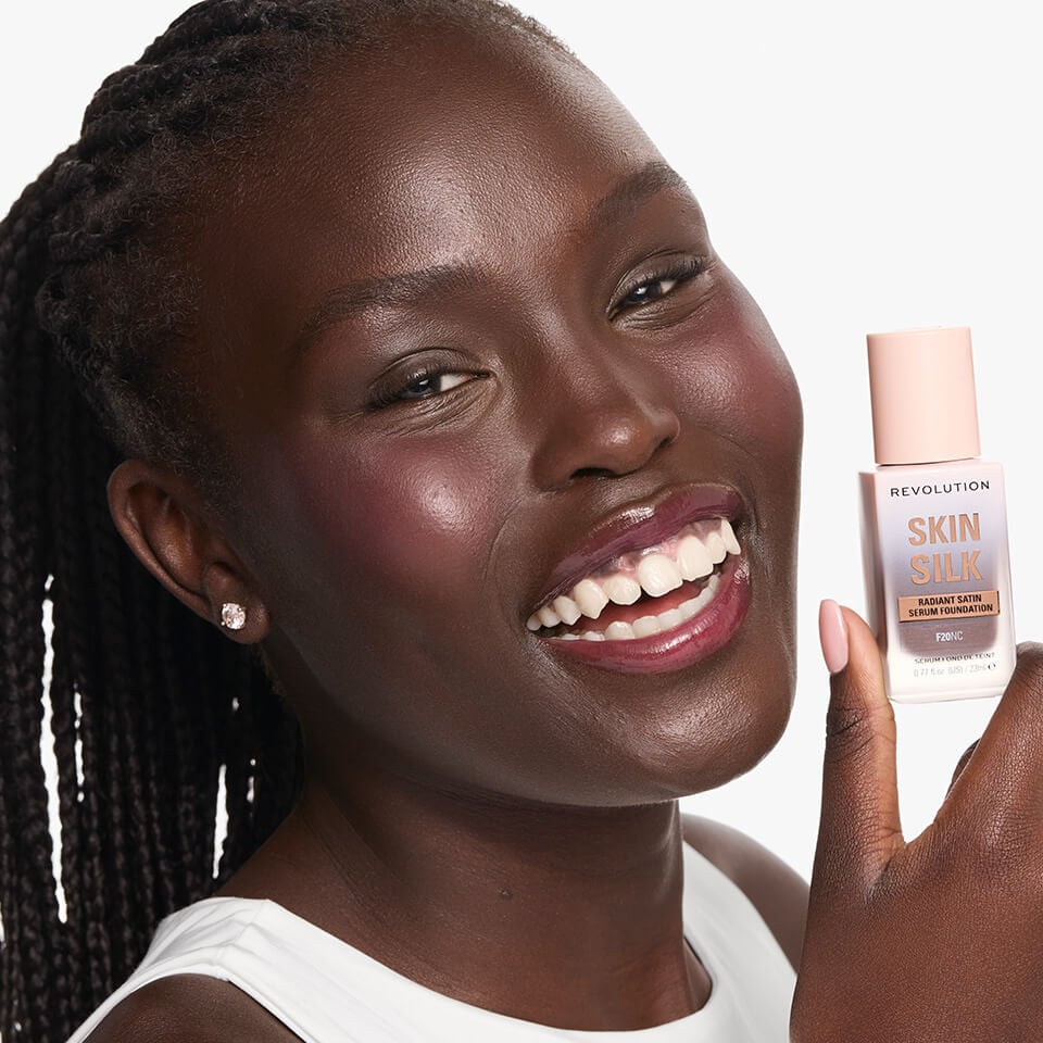 An Image of a model wearing and holding the Revolution Skin Silk Serum foundation